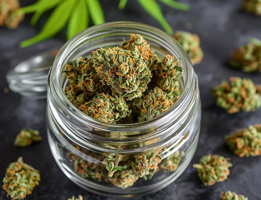 Fresh cannabis flower buds overflowing from a glass jar at Huff and Puff Dispensary