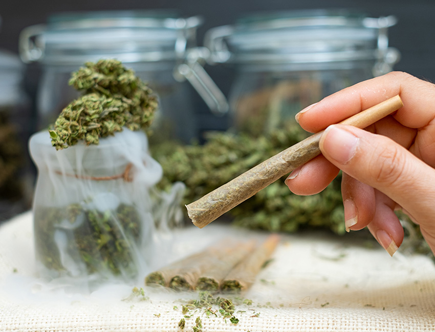 Hand holding a cannabis pre-roll joint at Huff and Puff Dispensary